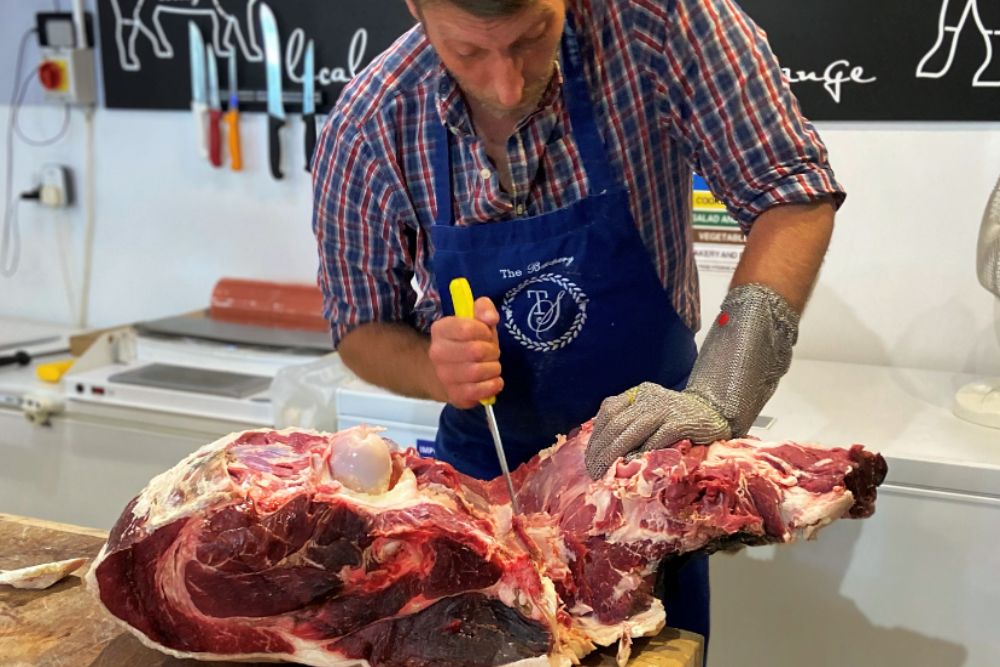 A butcher carving meat by hand